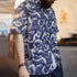 Person wearing a navy blue shirt with white graphic designs of people in various poses.